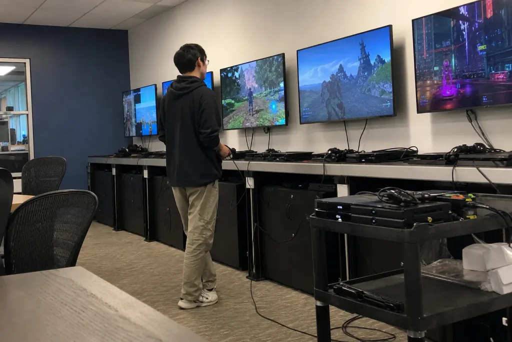 En speltestare håller i en kontroll framför flera skärmar under ett testpass av State of Decay 3.