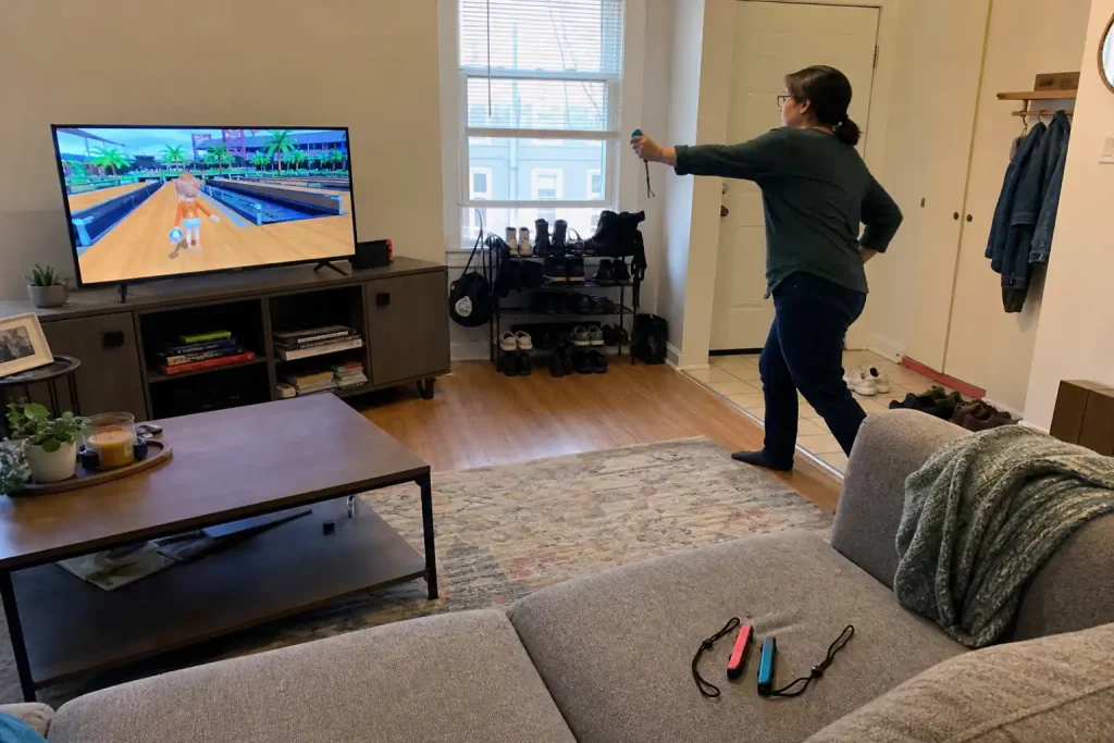 En person spelar Nintendo Switch Sports Resort med en Joy-Con i vardagsrummet framför TV:n.